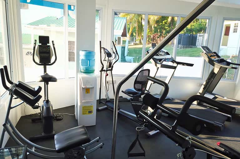 Bright fitness room with treadmills, exercise bikes, water cooler, and glass doors to outdoor patio