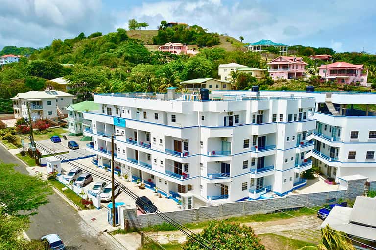 Waterfront apartment complex with white and blue exterior on hillside overlooking bay