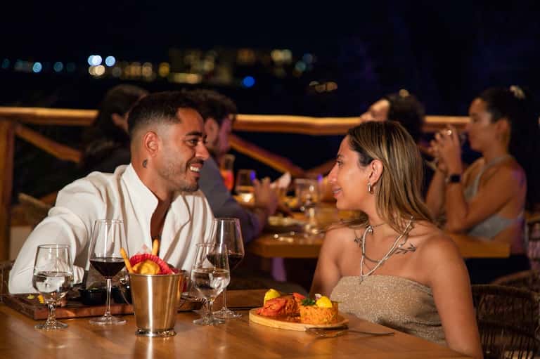 Couple dining at night overlooking city lights with wine glasses, appetizers, and ambient outdoor lighting