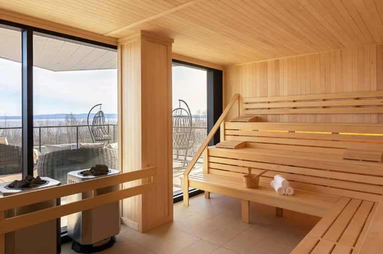 Luxury sauna with wooden interior, panoramic windows overlooking a snowy landscape and water view