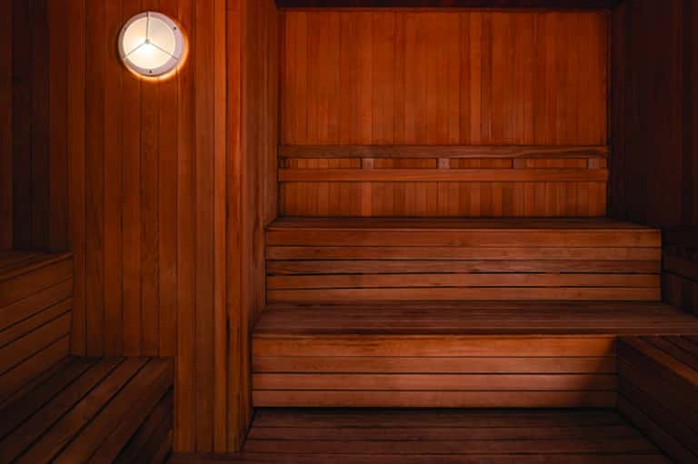 Wooden sauna interior with benches and circular porthole window