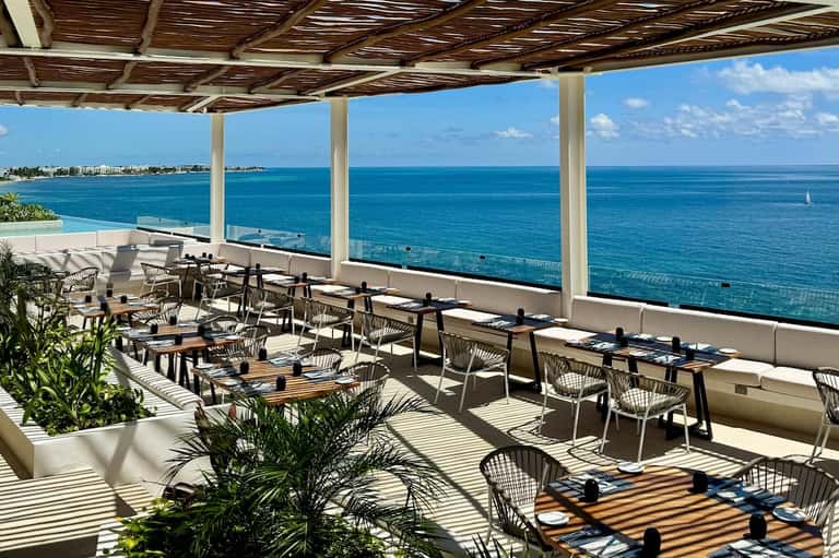 Upscale beachfront restaurant terrace with ocean views and modern dining setup