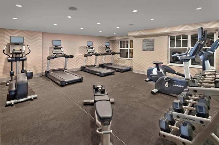Fitness center with treadmills, exercise bikes, dumbbells, and chevron-patterned accent wall