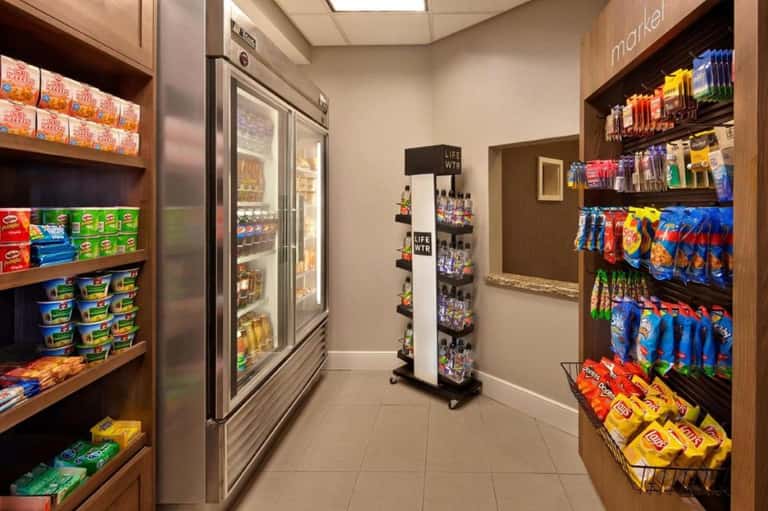 Hotel market with refrigerated beverage cases, snack shelves, and organized convenience items
