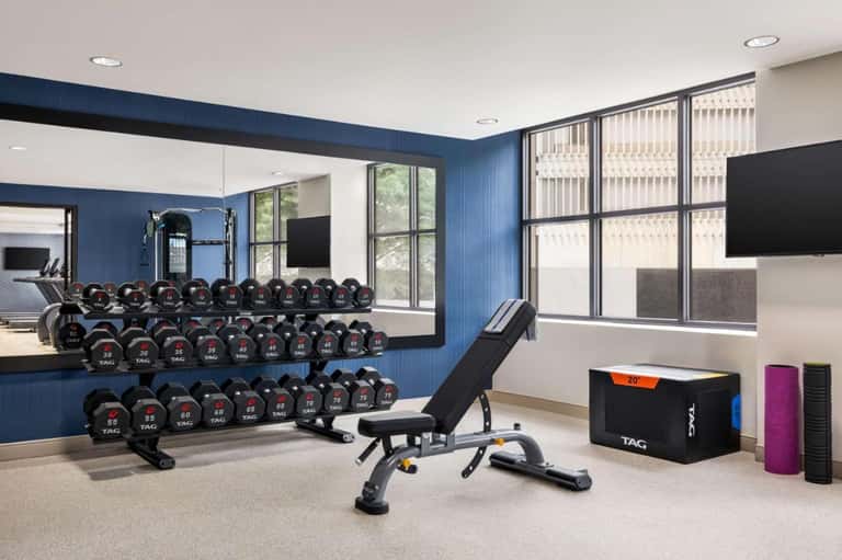 Contemporary fitness center with blue accent wall, dumbbell racks, and weight equipment