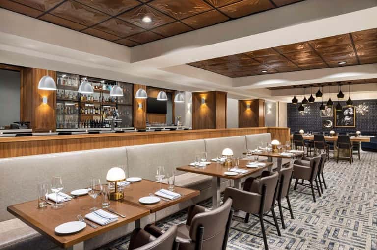 Fine dining restaurant with wooden bar, contemporary pendant lighting, and booth seating