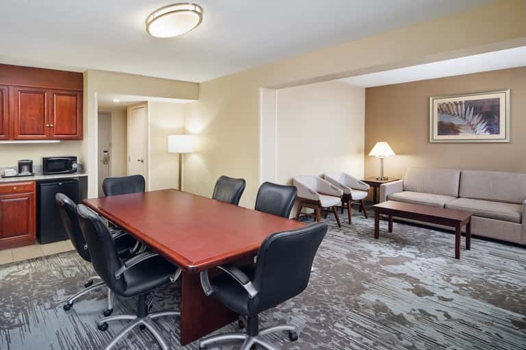 Hotel executive suite with conference table, meeting area, kitchenette, and living space