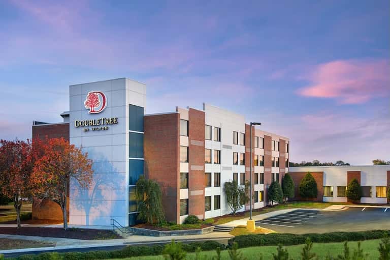 DoubleTree by Hilton hotel exterior at dusk with brick and white facade, landscaped grounds, and parking lot