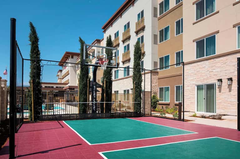 Basketball court at resort with colorful court surface and tall residential buildings