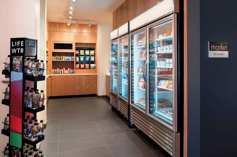 Hotel market convenience store with refrigerated beverage cases, snacks, and product displays