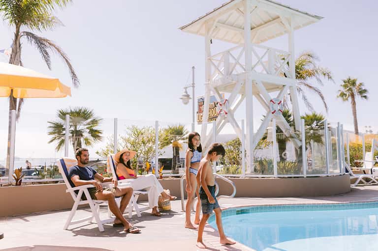 Family at resort pool with white observation tower and palm trees in background