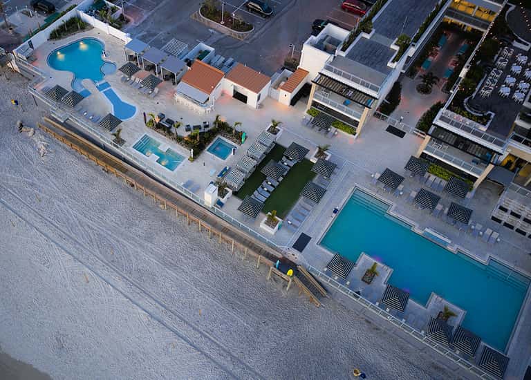 Aerial view of beachfront resort with multiple pools, loungers, and ocean access
