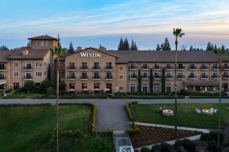 Westin hotel waterfront facade at sunset with manicured lawns and fire pit seating areas