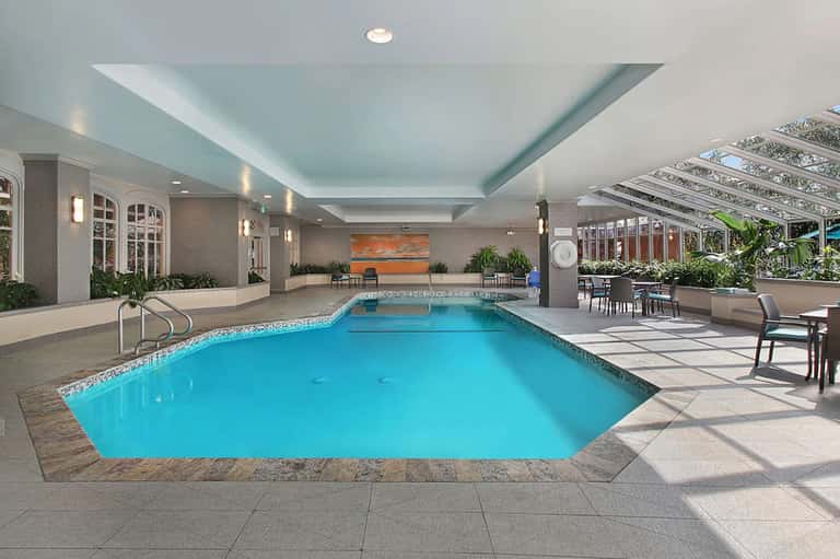 Indoor heated pool with high ceilings, natural light, and modern spa facilities