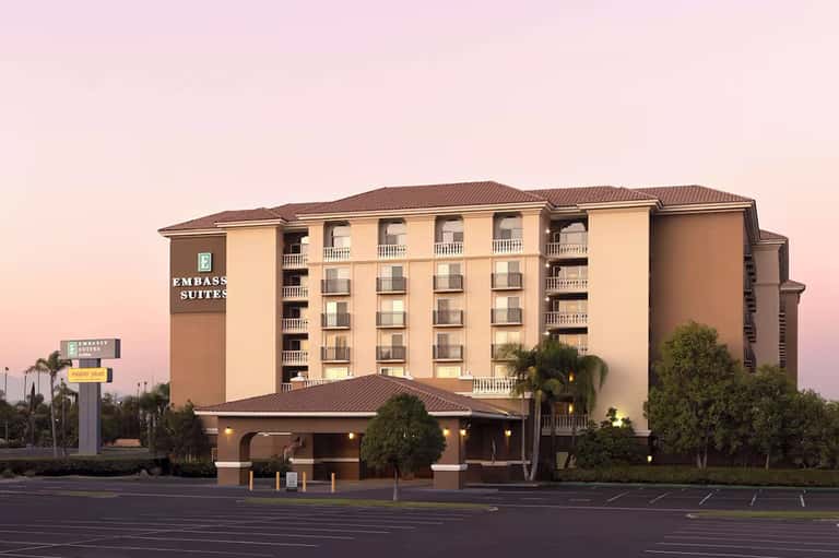 Embassy Suites hotel exterior at dusk with illuminated entrance and palm trees
