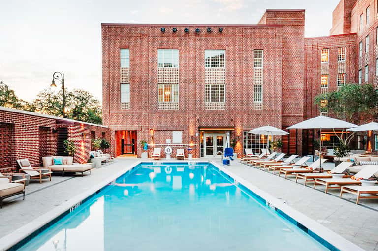 Rectangular lap pool in brick courtyard with lounge chairs and umbrellas