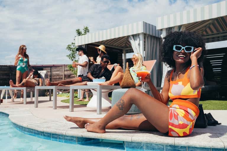 Resort pool party with guests relaxing poolside near modern cabana structure