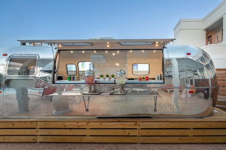 Vintage Airstream food truck with open service window and string lights on wooden platform