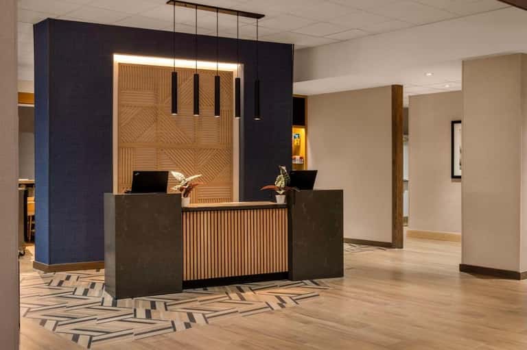 Hotel reception desk with dark blue accent wall, wood paneling, and geometric floor pattern in modern lobby