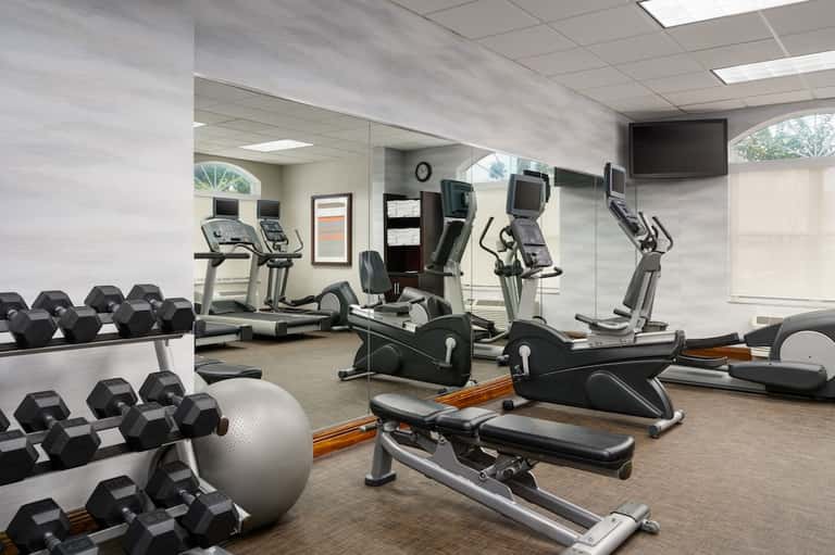 Fitness center with cardio equipment, dumbbells and mirrored walls