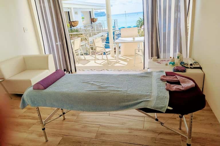 Beachfront hotel room with ocean views from balcony, bed with colorful pillows, and seating area