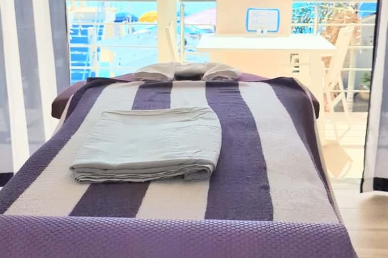 Beachfront bedroom with ocean view, purple and white striped bedding and balcony