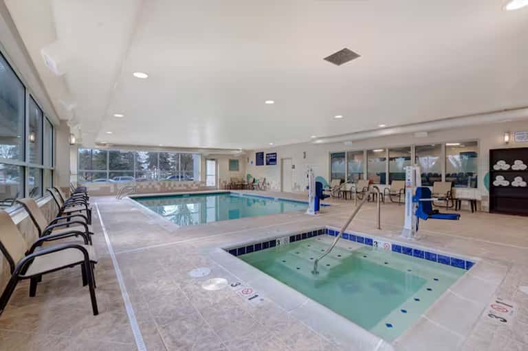 Indoor pool and hot tub facility with large windows and lounge seating area