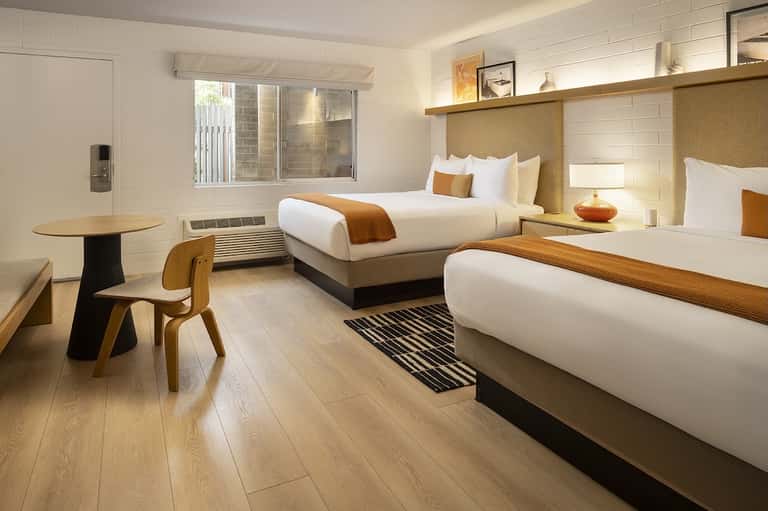 Modern hotel room with two queen beds, wood accents, and minimalist furnishings