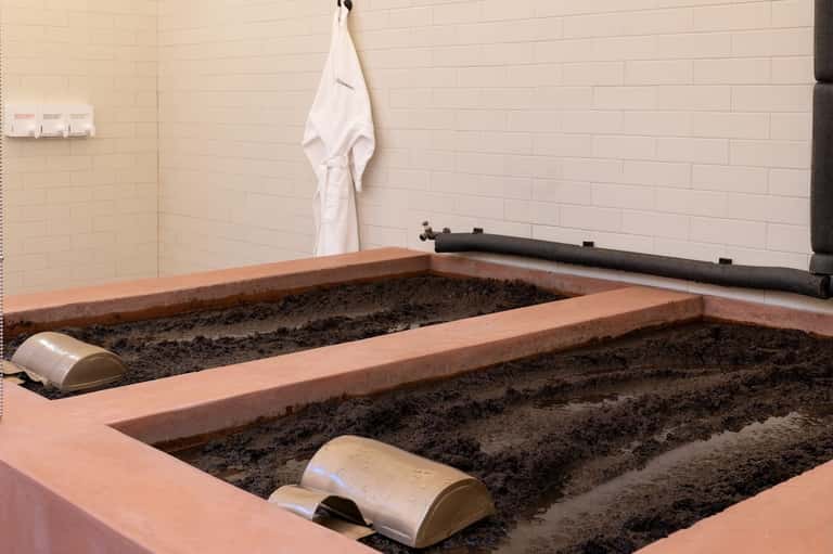 Spa treatment room under construction with large stone bathtubs and white tile walls