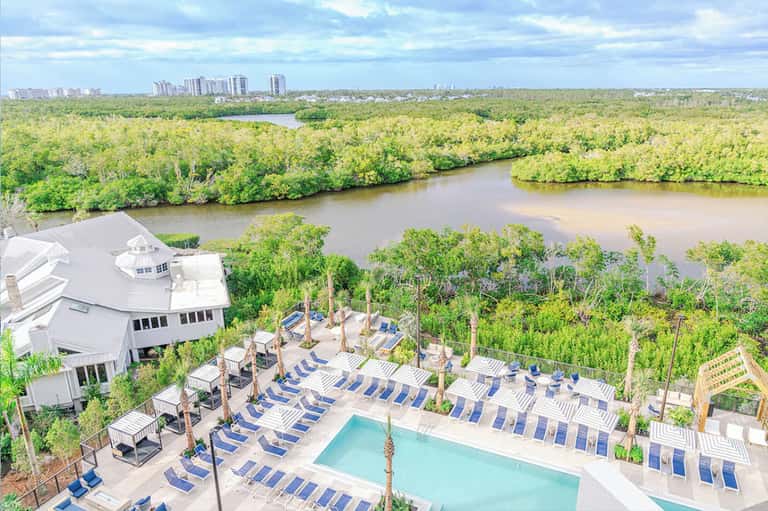 Aerial view of resort pool and deck overlooking mangrove wetlands and distant city skyline