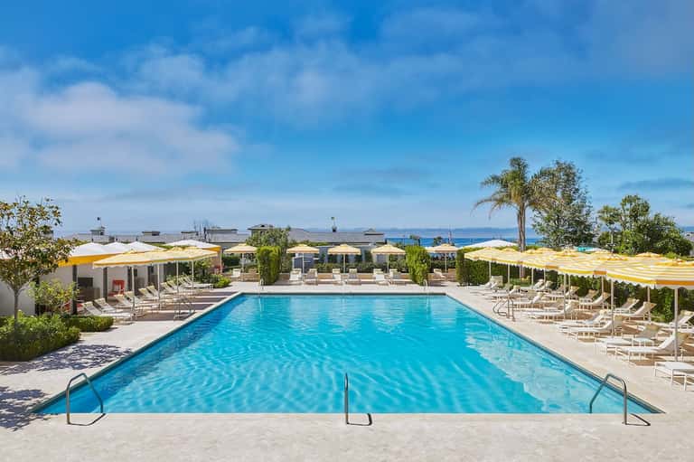 Olympic-sized pool with yellow umbrellas, lounge chairs, and mountain views on clear day