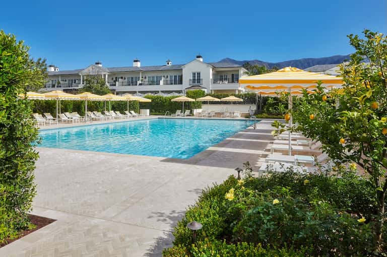 Resort pool with white loungers, umbrellas, and mountain views