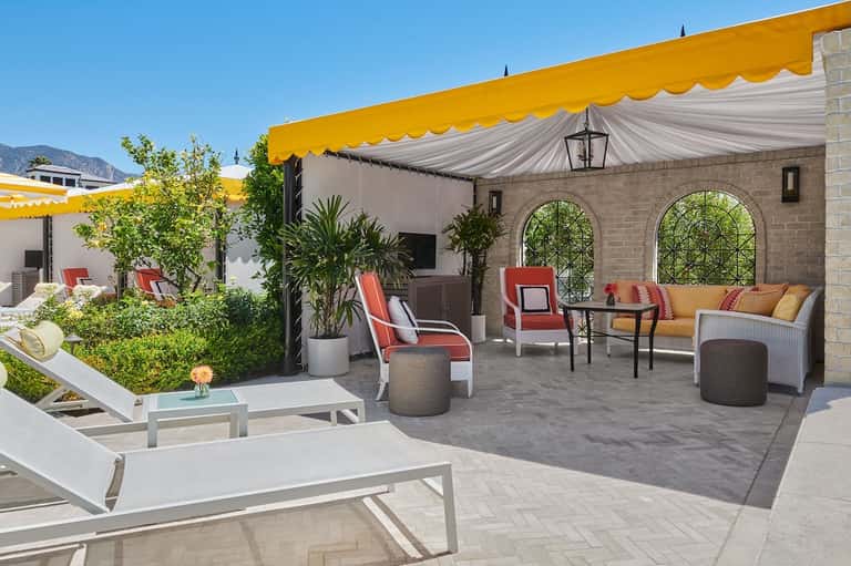 Upscale terrace with yellow and white striped awning, brick arches, red and white seating, and mountain views