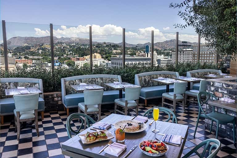 Upscale rooftop restaurant with city skyline views, blue seating, and fine dining setup