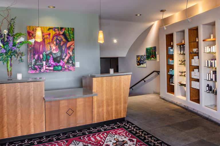 Contemporary hotel lobby with wooden reception desk, vibrant artwork, and retail shelving
