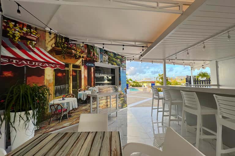 Covered restaurant terrace with views of resort pool and ocean horizon