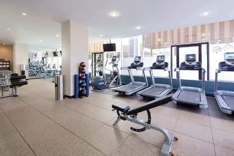 Bright fitness center with treadmills, exercise bikes, and floor-to-ceiling windows