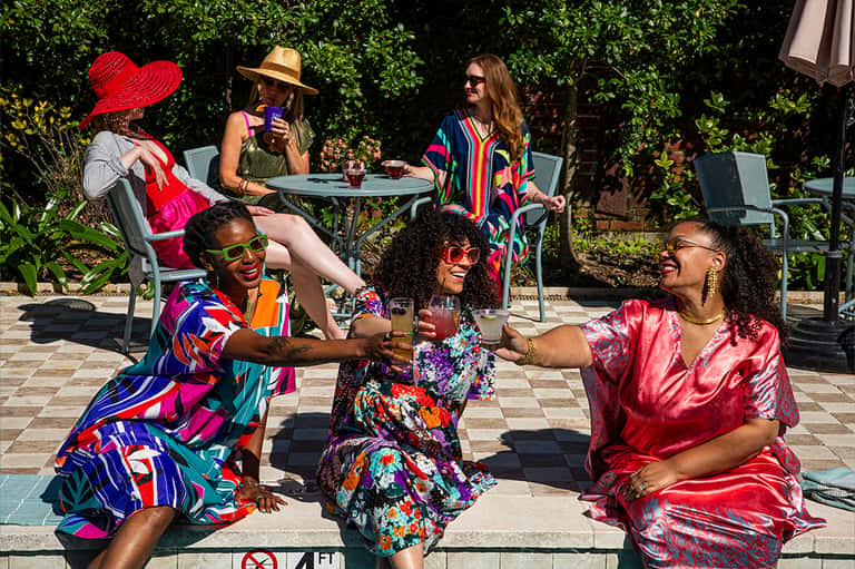 Diverse group celebrating outdoors in bright clothing at resort courtyard with greenery