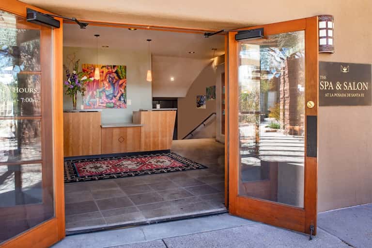 Spa and salon reception entrance with wooden doors, colorful artwork, and natural light