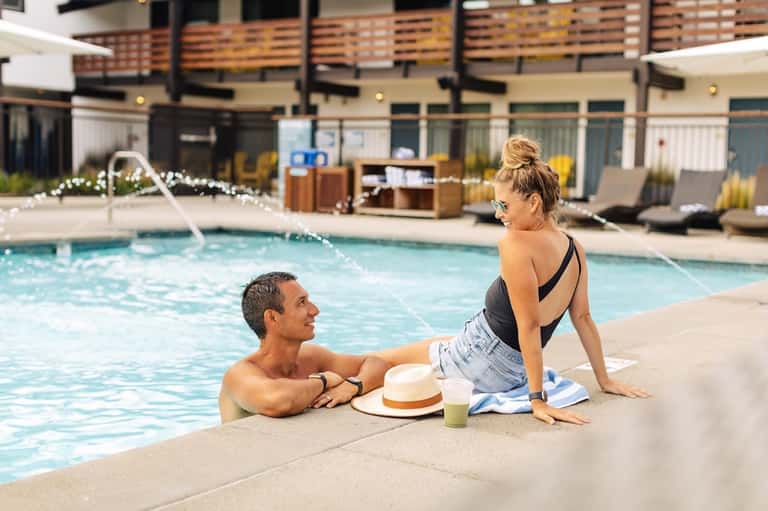Couple enjoying the pool deck at a modern resort with contemporary architecture and landscaping
