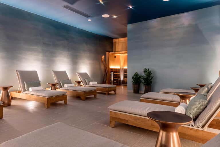 Indoor spa relaxation area with wooden lounge chairs, soft lighting, and potted plants
