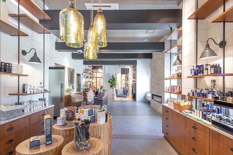Modern spa interior with wooden shelving, gold pendant lights, and polished concrete flooring