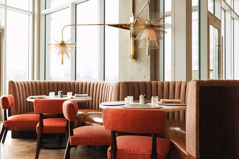 Fine dining room with taupe booths, gold pendant lights, and floor-to-ceiling windows