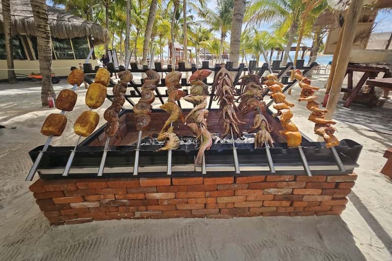 Beach barbecue display with grilled meats and seafood on skewers over open flames