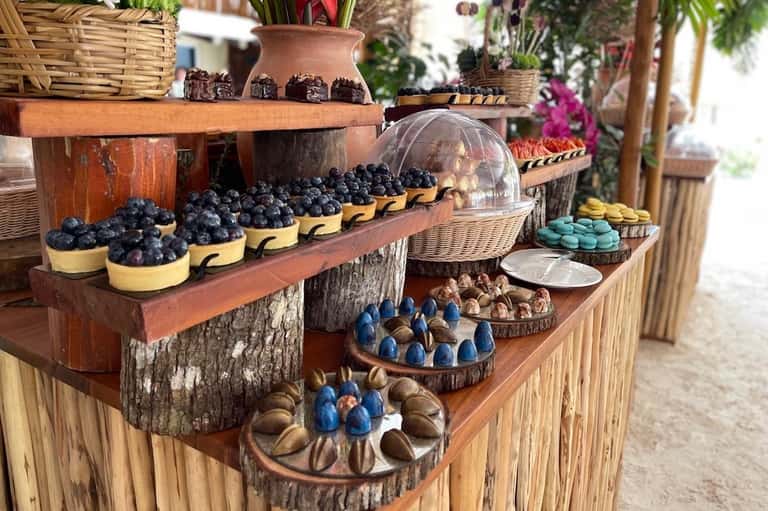 Rustic outdoor market display with blueberries, pastries, macarons, and decorative flowers