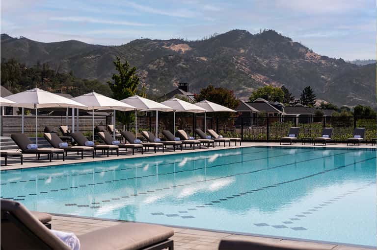Resort swimming pool with lap lanes, white shade structures, and mountain landscape views