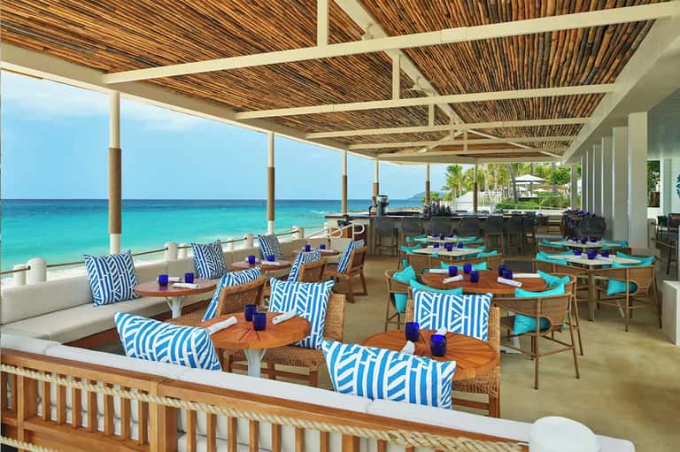 Elegant beachfront dining area with turquoise ocean views and blue patterned furniture