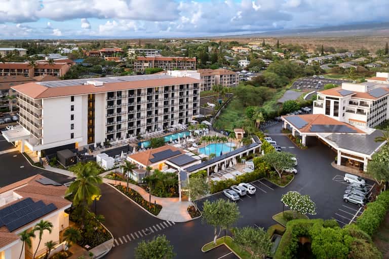 Aerial view of resort complex with pool, buildings, and surrounding landscape