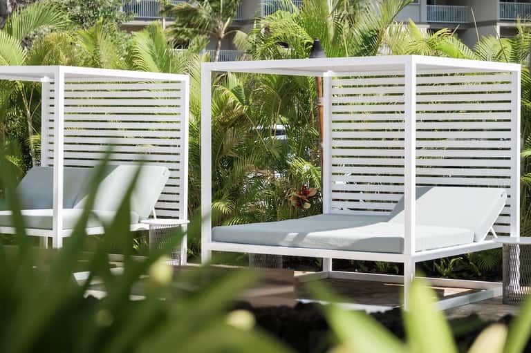Contemporary outdoor daybed with white canopy surrounded by tropical plants
