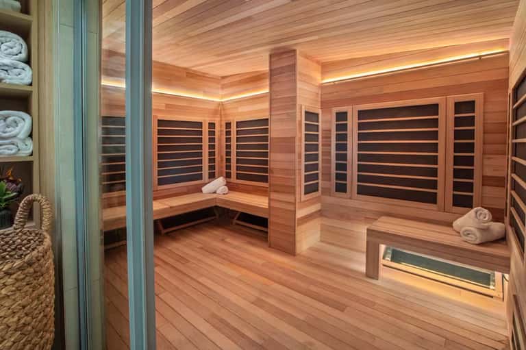 Wooden sauna interior with benches, infrared panels, and heated seating